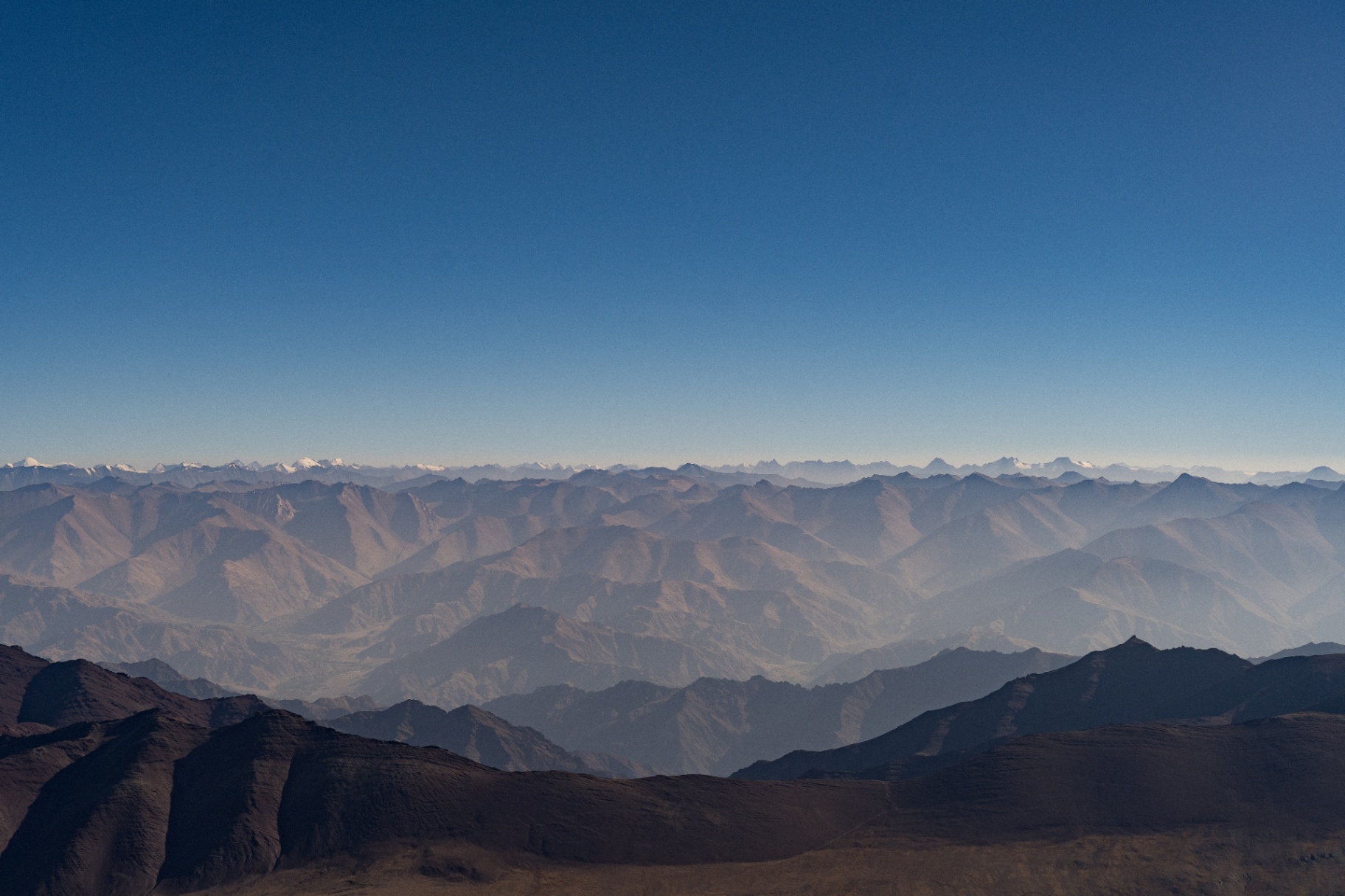 Des plages brumeuses sans fin s'éloignant à l'horizon sous un ciel bleu clair, Ladakh