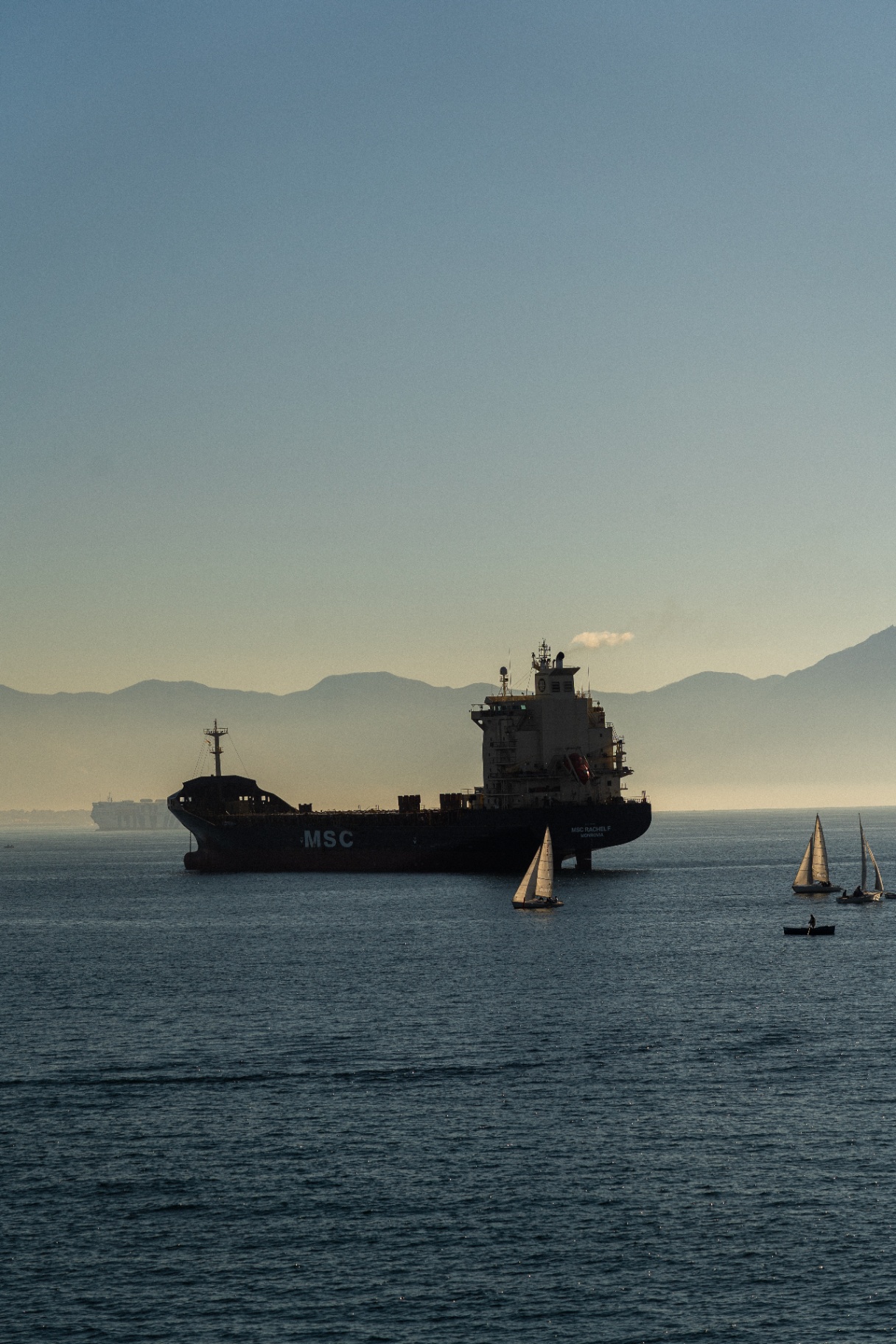 Cargo et petits voiliers dans la baie de Naples au crépuscule