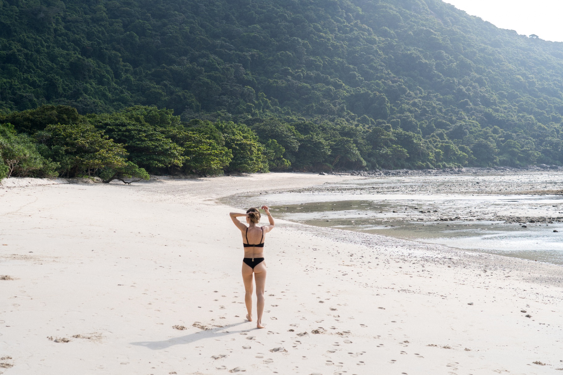 Marche sur la plage déserte au pied des falaises de jungle