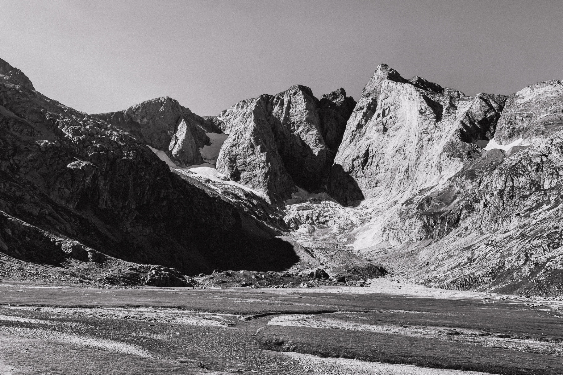 Vue monochrome de la face du Vignemale au-dessus d'une plaine de rivière en tresses
