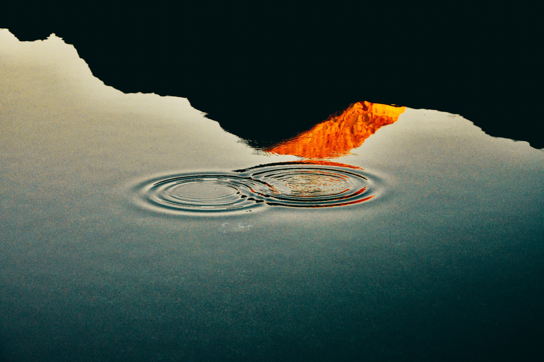 Ondes concentriques dans l'eau calme reflétant un sommet embrasé